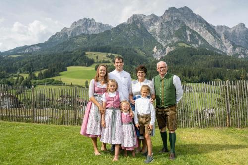 a family posing for a picture in front of a mountain at Hotel Riederalm in Leogang