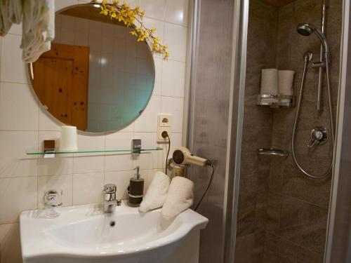 a bathroom with a sink and a mirror and a shower at Apartments home Niedermunthof, Villnöß in Funes