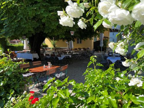 a table and chairs under a tree with white flowers at Landgasthof Rechenwirt in Elsbethen