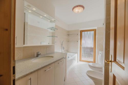 La salle de bains est pourvue d'un lavabo, de toilettes et d'un miroir. dans l'établissement Appartamenti Cèsa Sorèie Dolomiti, à Canazei