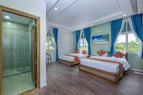 a bedroom with two beds and a shower at V&T Hotel in Phú Quốc