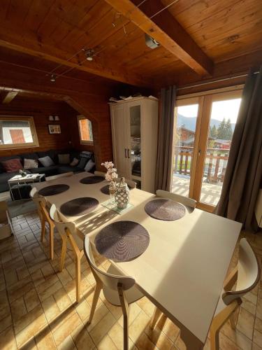 une salle à manger avec une table et des chaises blanches dans l'établissement CHALET FAMILIAL AU PIED DES PISTES ET COMMERCES, à Cohennoz