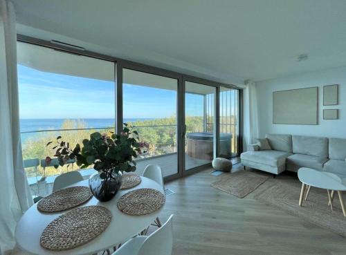 a living room with a table and chairs and a couch at PINEA Apartments Pobierowo z niesamowitym widokiem na morze oraz jacuzzi w wybranych apartamentach in Pobierowo
