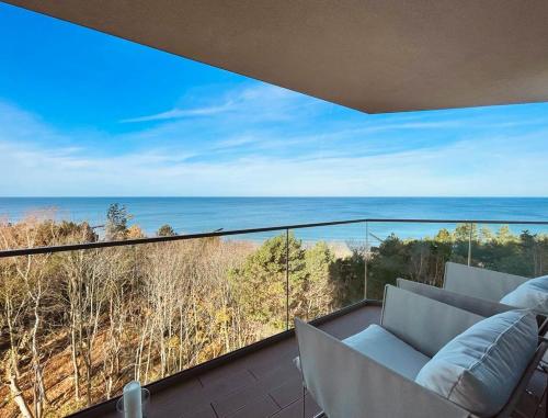 balkon z kanapą i widokiem na ocean w obiekcie PINEA Apartments Pobierowo z niesamowitym widokiem na morze oraz jacuzzi w wybranych apartamentach w Pobierowie