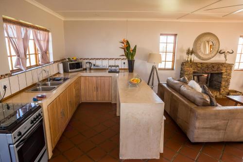 a kitchen and living room with a couch and a table at Kwetu Guest Farm in Swellendam