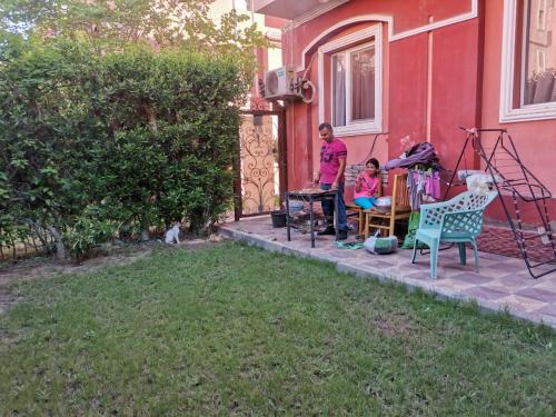 a woman and a child sitting on the porch of a house at Hotel apartment in Sheikh Zayed City in Sheikh Zayed