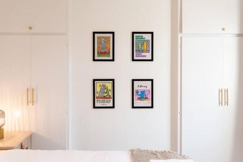 a bedroom with four framed pictures on a white wall at Bright & Airy 2BD - 10 mins walk to Chelt Centre! in Cheltenham