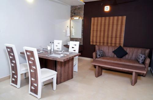 a dining room with a table and chairs and a couch at Lantern Apart Hotel in Perintalmanna