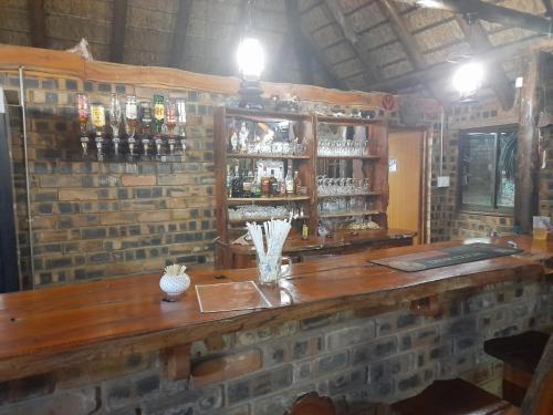 a bar with a brick wall with a wooden counter at Monkey Mountain Family Lodge in Gemsbokfontein