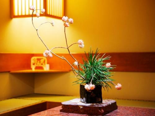 a vase with flowers on a table in a room at Kaneyamaen in Fujiyoshida
