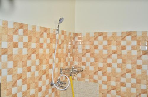 a shower with a hose in a tiled bathroom at Heart Of Africa Adventure and Apartments in Arusha