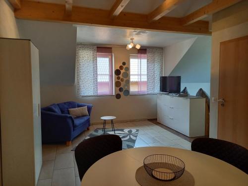 a living room with a table and a blue couch at Appartement Spatzennest in Mossautal