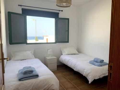 Duas camas com toalhas num quarto com janela em Salitre Apartamento em El Golfo