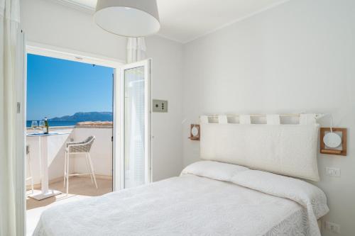een witte slaapkamer met een bed en een balkon bij S'Abba seafront apartments - Your House in Sardinia in Golfo Aranci