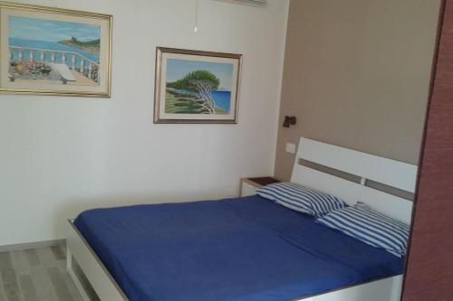 Schlafzimmer mit einem Bett mit blauer Bettwäsche und einem Bild in der Unterkunft Appartamento Valentina: relax e natura in Sirolo