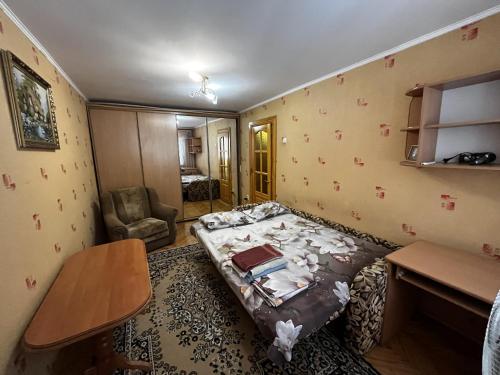 um quarto com uma cama, uma mesa e uma cadeira em Апартаменты рядом с парком центр em Vinnytsya