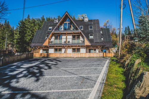 a house with a solar roof on a driveway at TatryTop Apartamenty Alpejski SPA in Kościelisko