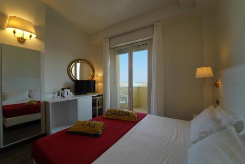 a bedroom with a large white bed with a red blanket at Hotel Imperial Beach - Dada Hotels in Rimini