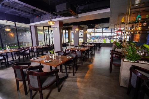 a restaurant with wooden tables and chairs and windows at Lantern Apart Hotel in Perintalmanna
