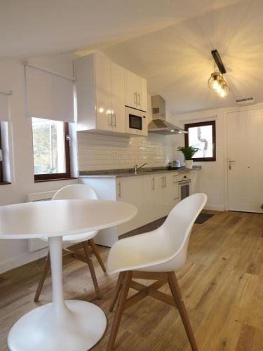 a white kitchen with a white table and chairs at Apartamentos la Garita - Casa Miro y Marianita - Cudillero in Cudillero