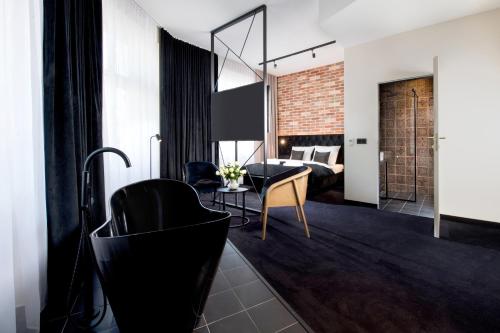 a living room with a black chair and a bedroom at Hotel Krupnicza 30 in Kraków