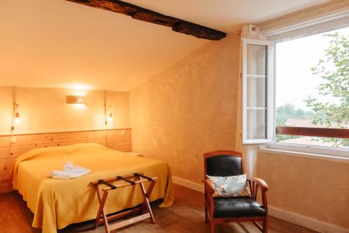 a bedroom with a bed and a chair and a window at Chambres Aguerria Hendaye in Hendaye