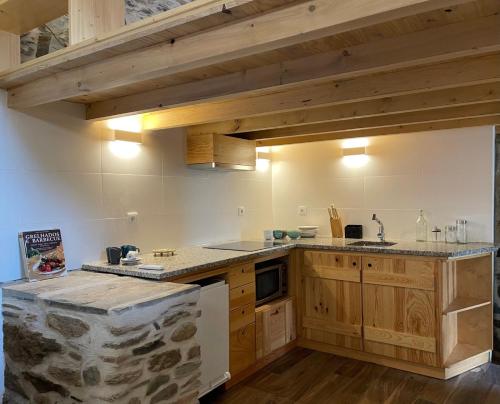 una cocina con armarios de madera y una pared de piedra. en acalma - sesmo, en Sarzedas