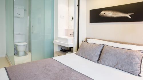 a bedroom with a bed and a bathroom with a fish on the wall at Hotel Denit Barcelona in Barcelona