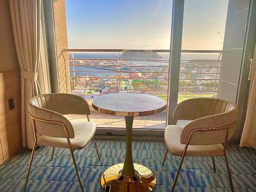 a room with a table and two chairs and a large window at Hotel bridge Seogwipo in Seogwipo