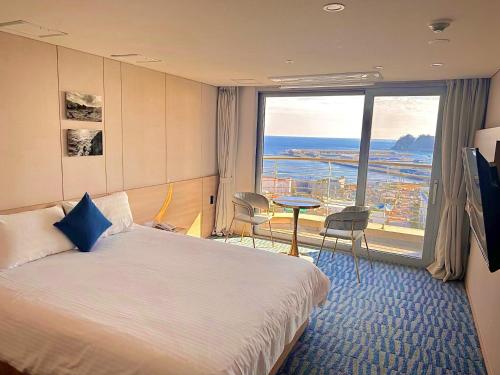 a hotel room with a bed and a large window at Hotel bridge Seogwipo in Seogwipo