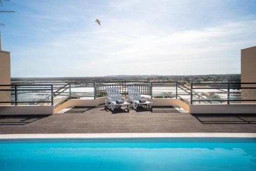 a balcony with a pool and chairs and a bird at Sovipral Homes Casa Marina in Olhão