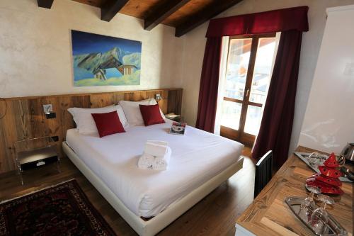 una camera da letto con un grande letto bianco con cuscini rossi di Le Charaban ad Aosta