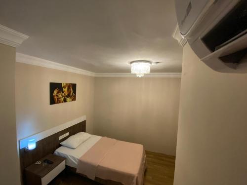 um pequeno quarto com uma cama e um lustre em DUVAHi OTEL KONAKLAMA em Adana