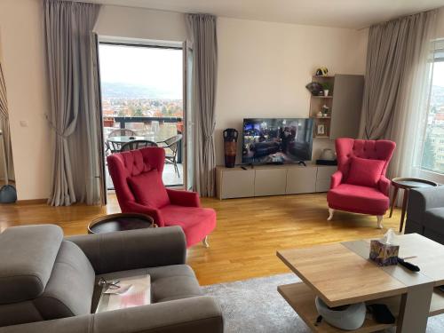 a living room with red chairs and a tv at شقة نهر اليجا in Sarajevo