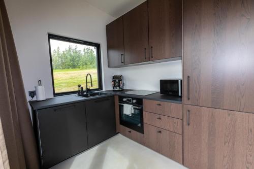 a kitchen with wooden cabinets and a window at North Mountain View Suites in Akureyri
