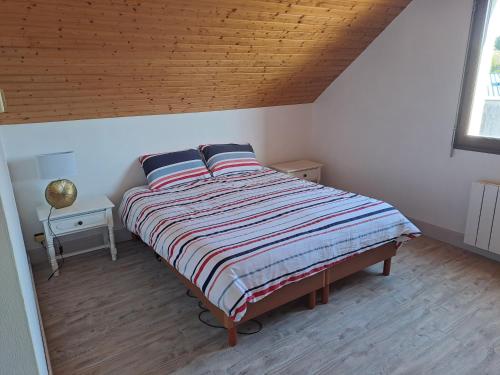 Ce lit se trouve dans une chambre dotée d'un plafond en bois. dans l'établissement IDAVRO, à Saint-Nicolas-du-Pélem