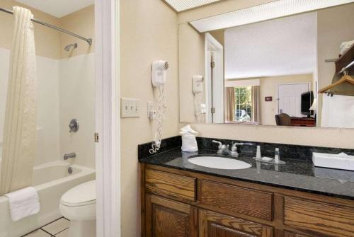 La salle de bains est pourvue d'un lavabo, de toilettes et d'un miroir. dans l'établissement Baymont by Wyndham Eufaula, à Eufaula