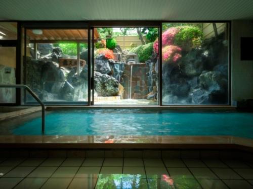 a swimming pool with a view of a garden through a window at Bessho Sasa in Fujiyoshida