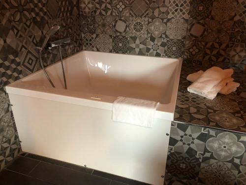 a white bath tub in a bathroom with tiles at V E R O N E - Rooms & Suites - Liège - Rocourt in Liège
