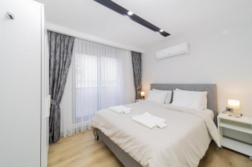 a white bedroom with a large bed and a window at Chic Flat with Central Location in Muratpasa in Antalya