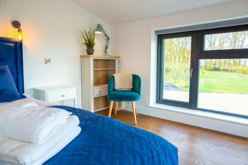 una camera con un letto e una sedia e una finestra di Orchard Barn - Luxury 4 BD Barn Conversion! a Fladbury