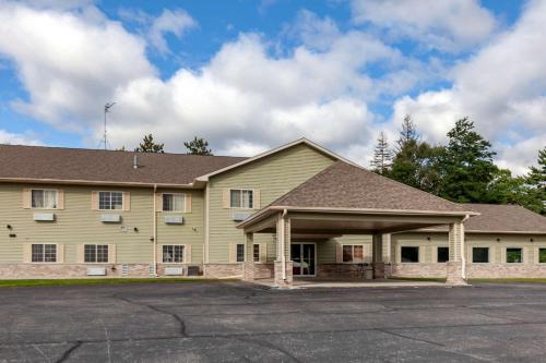 a large yellow house with a parking lot at Quality Inn Redgranite in Redgranite