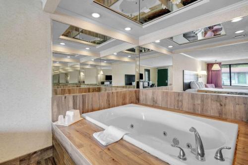 uma grande casa de banho com uma banheira e um espelho grande em Days-Inn by Wyndham Liverpool-Syracuse em Liverpool