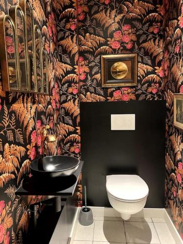 La salle de bains est pourvue de toilettes et de papier peint à fleurs. dans l'établissement St Nazaire Jardin des plantes superbe appartement, à Saint-Nazaire