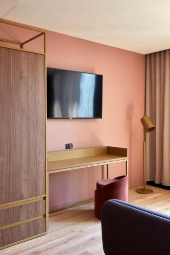 a room with a desk and a television on a wall at Quincy Hotel Melbourne in Melbourne