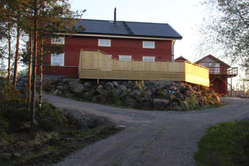 una casa roja con una valla de madera junto a una carretera en Lillesjö stuguthyrning en Bäckefors