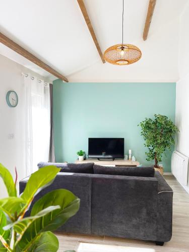 a living room with a couch and a tv at Charmante Maisonnette au calme / Jardin privatif in Clermont