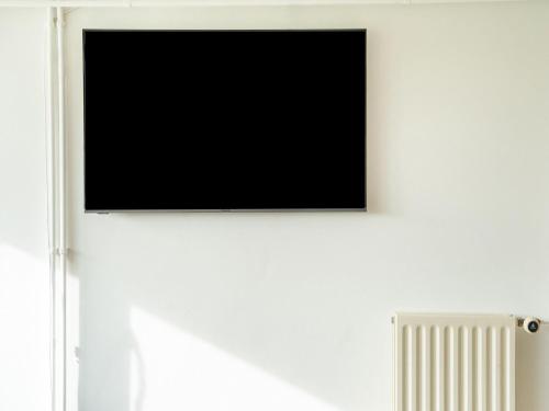 a flat screen tv on a white wall with a radiator at Holiday Home in Silvolde with Hot Tub in Silvolde