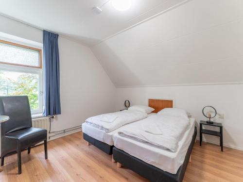 a bedroom with two beds and a chair and a window at Holiday Home in Silvolde with Hot Tub in Silvolde
