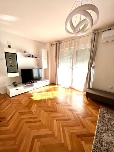 a living room with a hard wood floor and a chandelier at Lux Apartman Casablanca in Pluzine